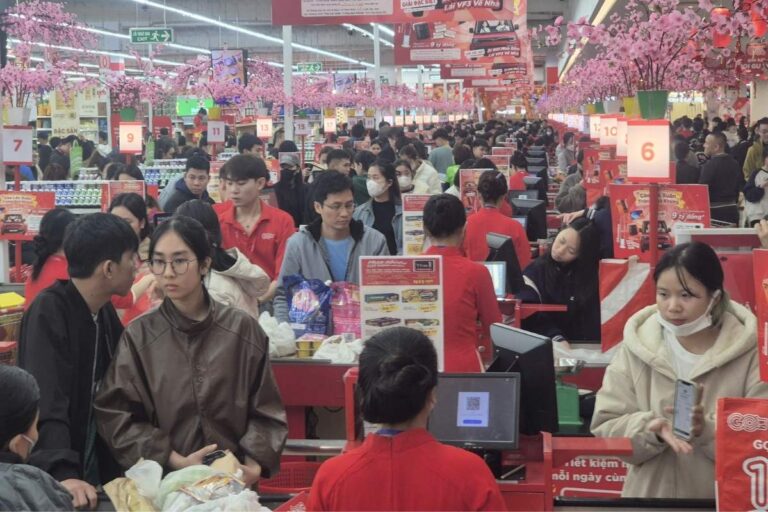 越南超市於2026年農曆新年前夕湧現採購人潮，顧客在收銀台前等待結帳。零售商表示春節期間客流量與銷售額較促銷初期成長兩至三成。圖片來源：越南勞動報（Lao Động）